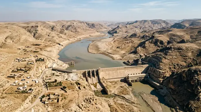 Vue aérienne d'un barrage dans une région aride du Moyen-Orient, illustrant la tension croissante sur les ressources en eau.