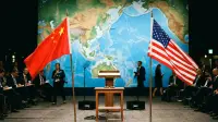 Drapeaux chinois et américain se faisant face devant un planisphère de l'Indo-Pacifique, symbole de la rivalité entre Pékin et Washington.
