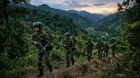 Soldats colombiens en patrouille dans une zone montagneuse boisée le long de la frontière avec le Venezuela, au crépuscule.