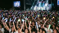 Foule de spectateurs brandissant des lightsticks lumineux lors d'un concert de K-pop nocturne.