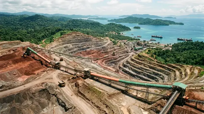 Vue aérienne de mines de nickel à ciel ouvert dans l'archipel indonésien, avec des convoyeurs de minerai rougeâtre et des forêts tropicales en arrière-plan