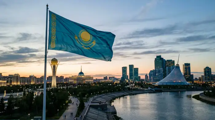 Le drapeau bleu et or du Kazakhstan flottant devant la silhouette moderne d'Astana, carrefour entre l'Est et l'Ouest.