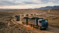 Convoi de camions chargés de charbon traversant le désert de Gobi vers la frontière chinoise, illustrant la dépendance minière mongole.