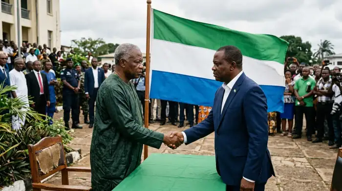 Une poignée de main politique devant le drapeau de la Sierra Leone, symbole fragile d'un accord d'unité nationale sous tension.