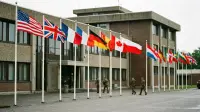 Drapeaux de pays alliés alignés devant un quartier général militaire, symbole de la défense collective